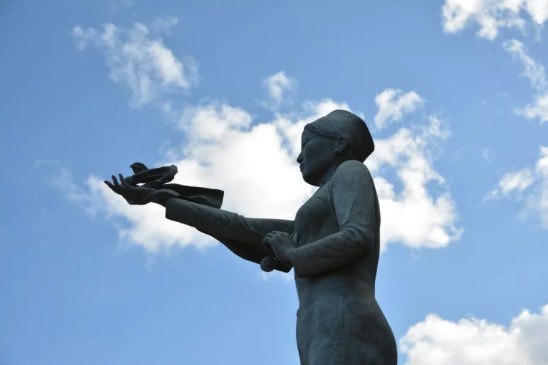 Statue releasing a bird against a blue sky
